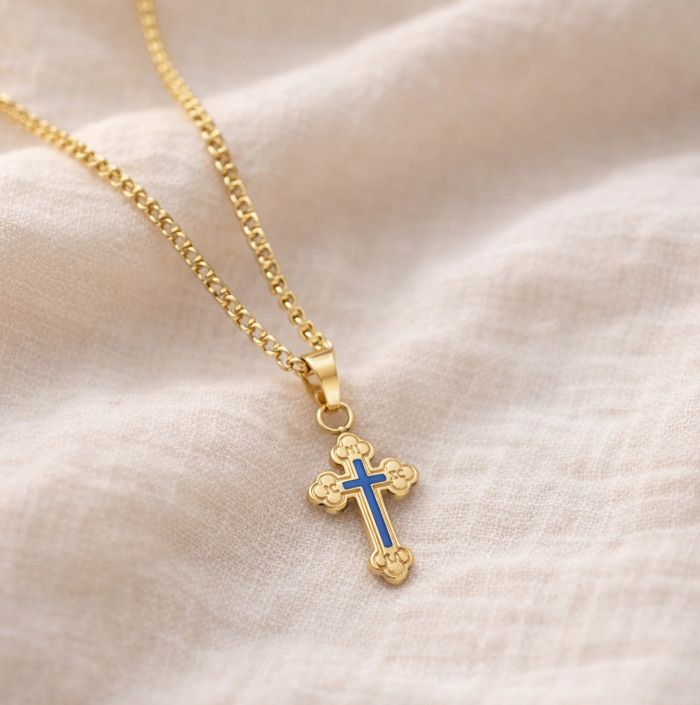 Gold cross necklace with blue center on a beige fabric Christian faith jewelry 